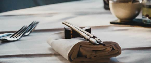 Asiatische Küche authentisch genießen Gedeckter Tisch mit Serviette, Besteck & Essstäbchen