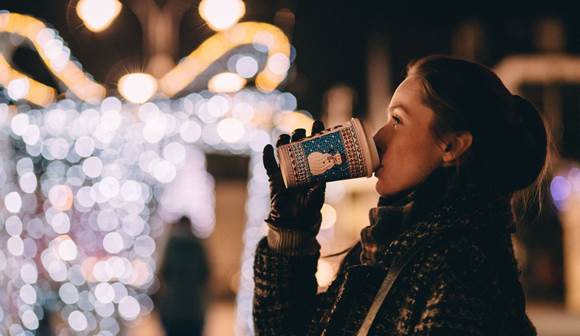 Besuchen Sie einen der vielen romantischen Adventmärkte in unserer näheren Umgebung Frau trinkt Heißgetränk aus Becher auf Weihnachtsmarkt