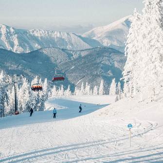 Entdecken Sie das Skigebiet Stuhleck in Ihrem Ski- und Thermenurlaub in Niederösterreich Skipiste mit Skifahrern und Sessellift