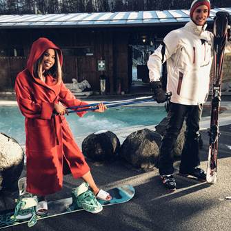 Therme und Ski – im Linsberg Asia Resort erleben Sie die ganze Bandbreite dieses Versprechens Skifahrer in Skigewand und Snowboarderin in Bademantel vor Außenpool