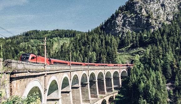 Genießen Sie herrliche Ausblicke bei einer Fahrt mit der Semmeringbahn Zug fährt über Viadukt in Berglandschaft